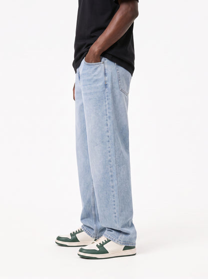 Model wearing B704 men's wide-leg denim jeans in Soft Light Blue, side view